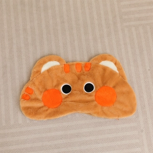 Detailed view of plush animal sleep mask with soft orange faux fur and cartoon eyes