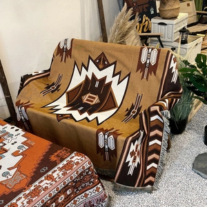 Bohemian geometric totem camping blanket in caramel tones with fringe on gravel background