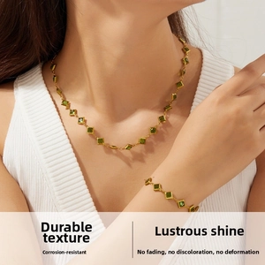 Close-up of vintage gold stainless steel jewelry set with square green glass stones