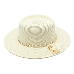 Détail du chapeau de paille beige avec chaîne dorée, perles blanches et pompons