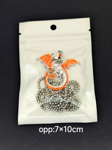 Close-up of a silver dragon pendant with orange enamel inlay in a clear storage pouch