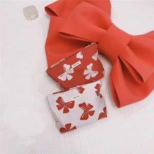 Flat lay of red and white canvas cosmetic bags with bow prints and brand labels
