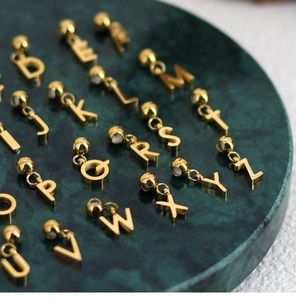 Close-up of golden A-Z alphabet pendants displayed on green marble plate