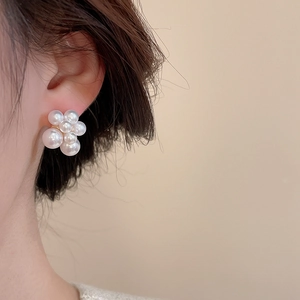 Close-up of elegant pearl cluster flower earrings worn on ear with soft lighting