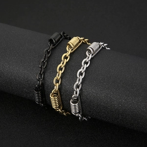 Three O-chain stainless steel bracelets in black, gold, and silver on a dark stand