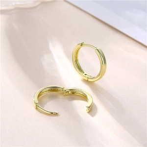 Minimalist 18k gold plated hoop earrings displayed on an elegant pink silk background