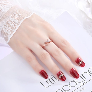 Detail of rose gold cutout ring featuring a triangle gemstone and letter L on a model hand
