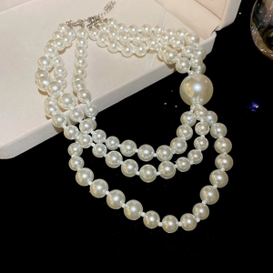 Detail view of a triple-strand pearl necklace with large focal pearl in a velvet box