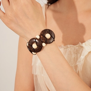 Close-up of bohemian wide elastic bracelet with natural coconut shell discs and cream beads