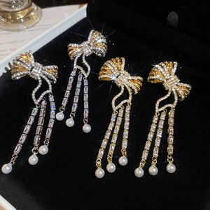 Detail of bow earrings with crystal tassels and pearls on black velvet display box