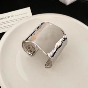 Detail of silver textured wide cuff bracelet with hammer pattern on white ceramic