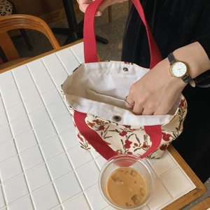 Floral corduroy tote bag with red handles on a cafe table during lunch commute