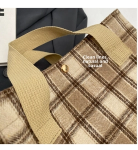 Detail of plaid canvas tote bag showing tartan pattern and gold metal button closure
