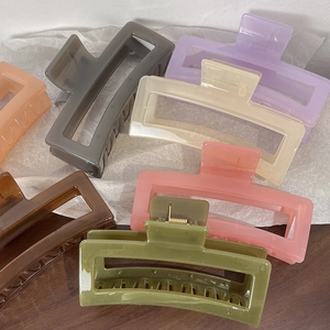 Top view of large rectangular matte claw clips in various pastel colors on a wooden table