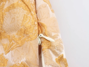 Detailaufnahme der goldenen Jacquard-Stoffstruktur mit weißem unsichtbarem Reißverschluss