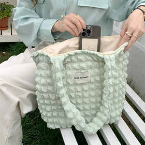 Detail of mint green puffy cloud tote bag featuring bubble texture and brand label