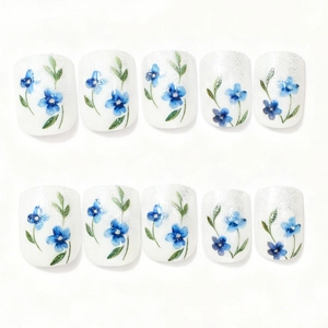 French pastoral style press-on nails with blue floral and green leaf patterns on white