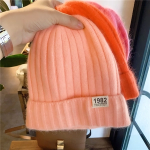 Detail of warm knitted beanie hats showing plush texture and 1982 label in various colors