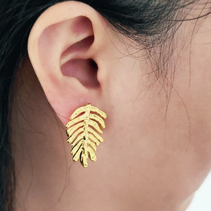 Elegant gold-plated leaf drop earrings with hollow veins shown on a model's ear