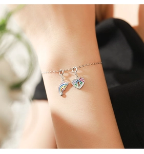 Detail of silver chain bracelet with rainbow crescent moon and heart-shaped lock pendants