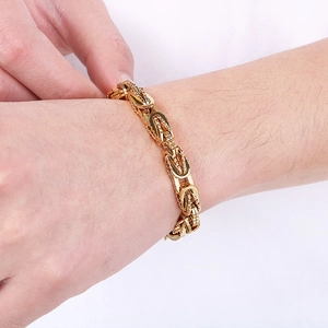 Dettaglio di un bracciale a catena bizantina in acciaio inossidabile dorato su un polso maschile