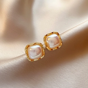 Dettaglio di orecchini a perno quadrati vintage in oro con perle su seta pregiata