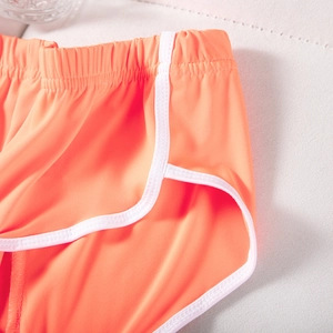 Detail der orangefarbenen Sportshorts mit weißem Rand und elastischem Bund auf Netzstoff