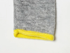 Macro detail of thick knit sweater cuff with gray texture and neon yellow contrast hem