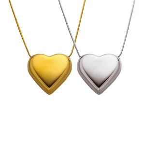 Pendentifs cœur poli en or et argent avec chaîne serpent sur fond blanc épuré
