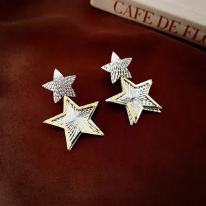 Elegant gold and silver plated star drop earrings on a sophisticated dark red fabric background