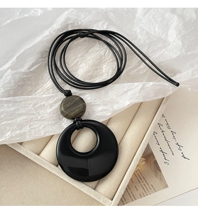 Detail of minimalist black agate round pendant necklace on white velvet jewelry tray