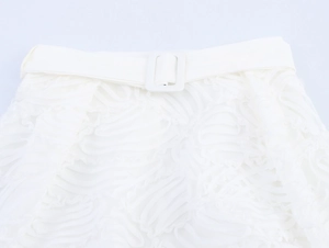 Détail de la taille de la jupe en dentelle blanche avec boucle et texture ondulée