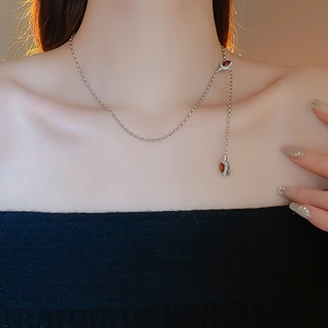 Detail of silver snake chain necklace with teardrop red gemstones on elegant collarbone