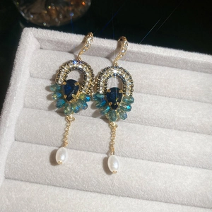 Détail de boucles d'oreilles vintage en or avec cristaux bleus et perle blanche