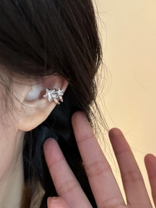 Detailed view of silver zircon star ear cuff worn on the ear bone for women