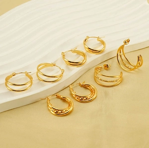 Detailed view of assorted layered gold C-shape hoop earrings on white stone display