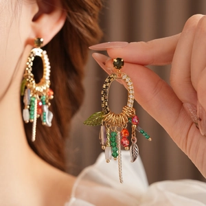 Detail of bohemian gold leaf tassel earrings with colorful beads and metal fringe