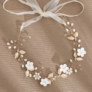 Detail of bridal hair comb with white ceramic flowers, gold leaves and pearls
