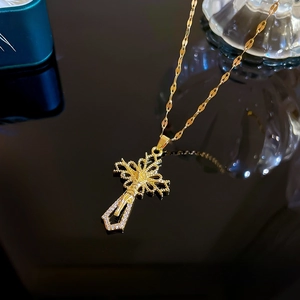 Close-up of gold titanium cross necklace with micro-pave diamonds on black mirror