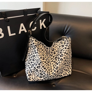 Detail of leopard print canvas tote bag with adjustable black strap on leather sofa