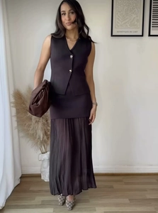 Detail of dark brown knit vest with gold buttons and pleated skirt ensemble