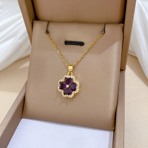 Detailed macro view of a gold clover necklace with purple heart gems and zircon pavé border