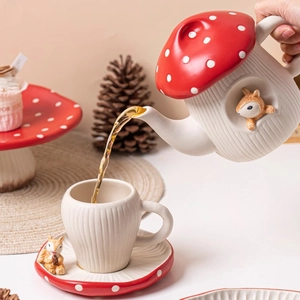 Close-up of pouring tea from a red mushroom ceramic teapot into a squirrel mug