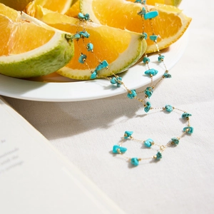 Detail of blue natural stone hand chain wrapped around fresh orange slices