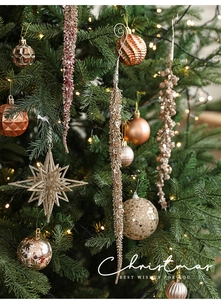 Close-up of champagne gold Christmas ball ornaments and glitter icicles on a festive tree