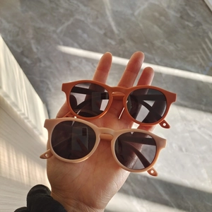 Detail view of matte orange and beige flexible silicone sunglasses for toddlers