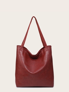 Détail de la texture en cuir ciré rouge et des coutures sur un grand sac cabas
