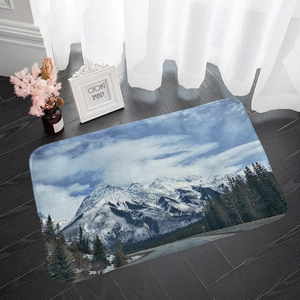 Detailed snow mountain landscape flannel rug placed on dark wood floor in home setting