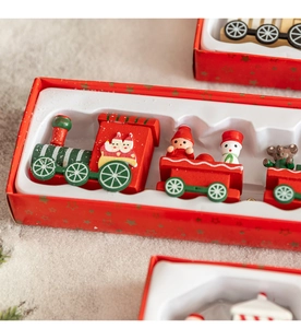 Close-up of a wooden Christmas train set with festive characters in a red gift box