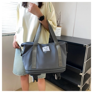 Gray travel bag featuring built-in spinner wheels and an expandable storage compartment
